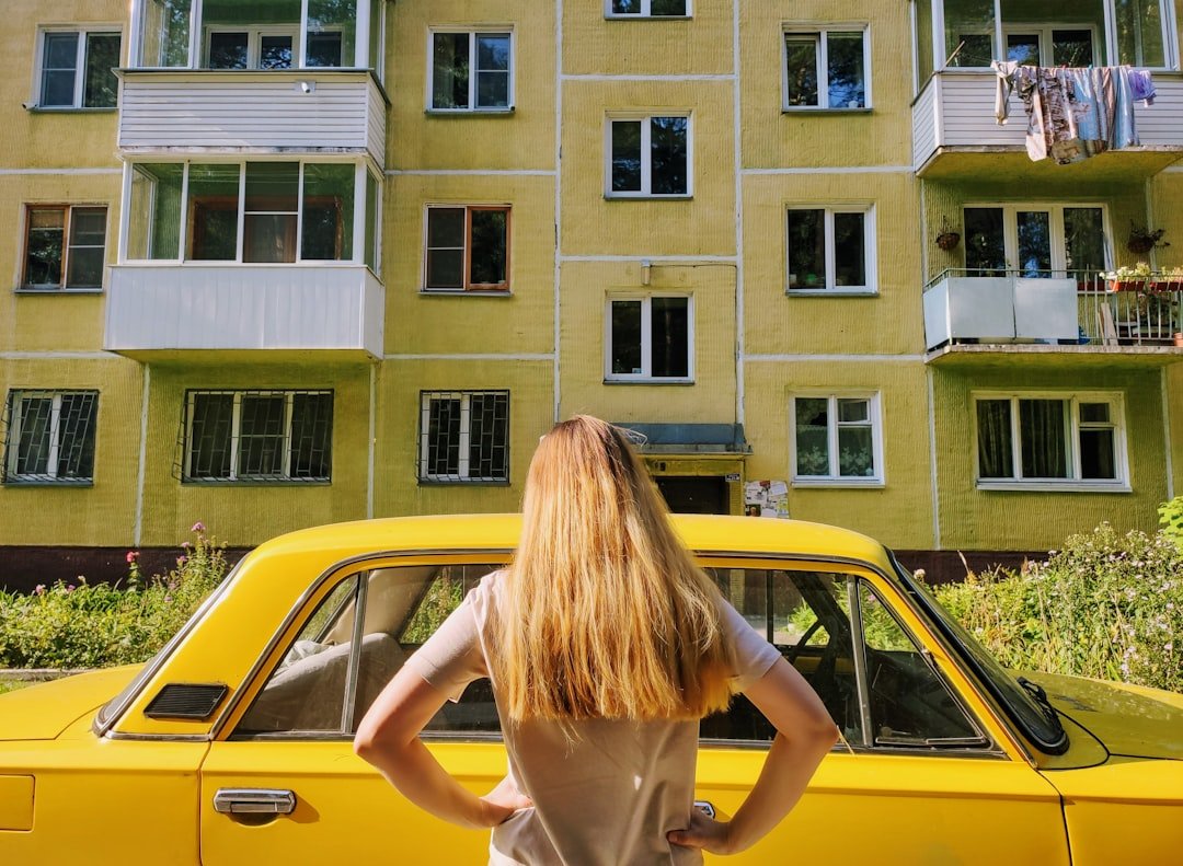woman in pink tank top leaning on yellow car