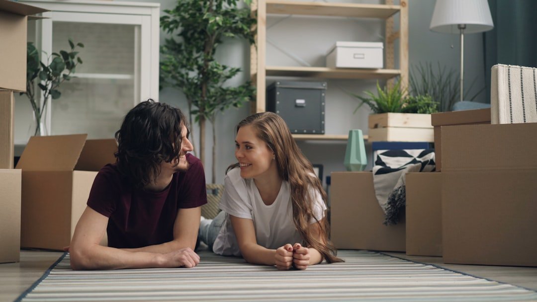 a man and a woman laying on the floor in front of moving boxes