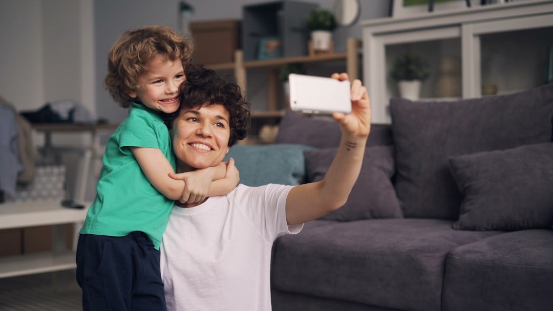 a woman holding a child and taking a picture with a cell phone