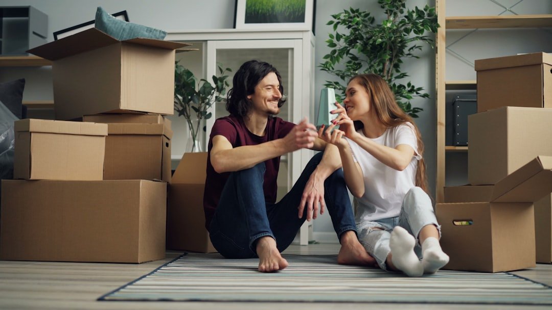 a man and a woman sitting on the floor surrounded by boxes
