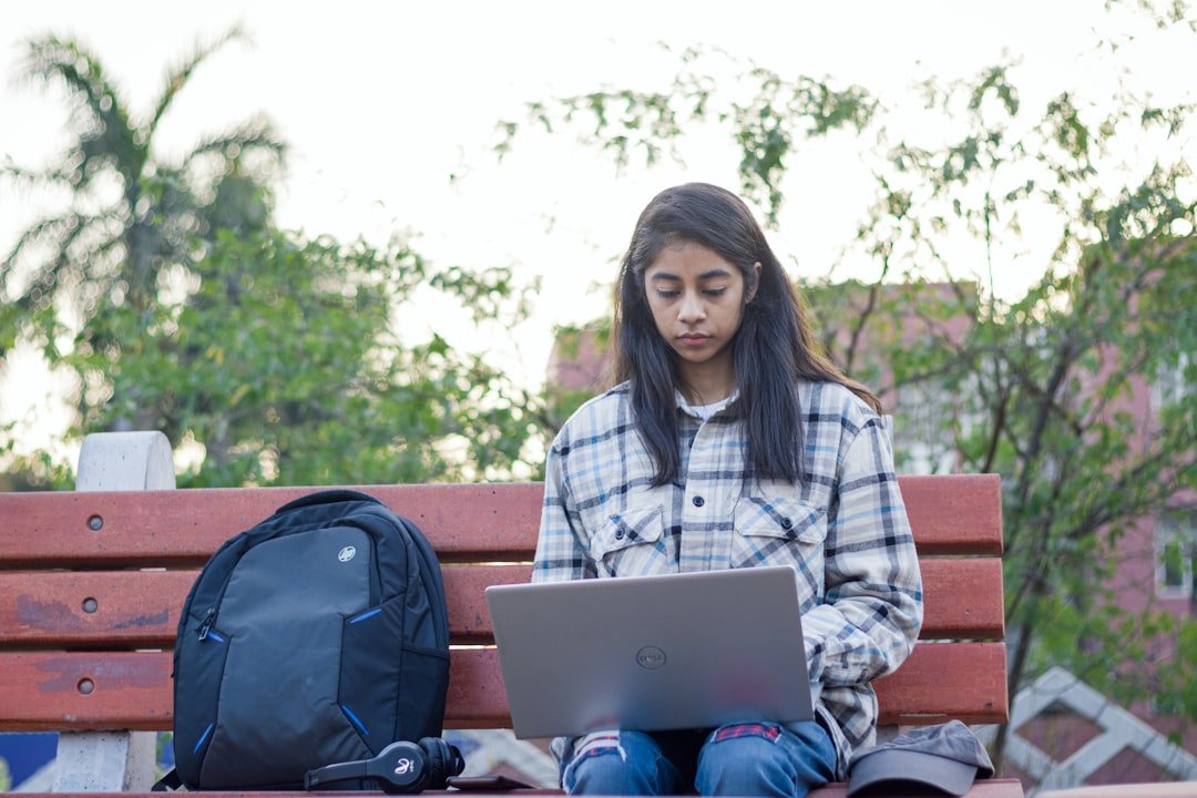 a woman sitting on a bench with a laptop