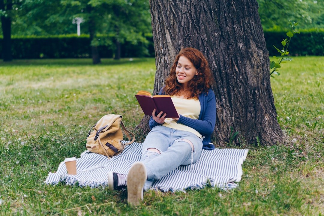 a woman sitting under a tree reading a book