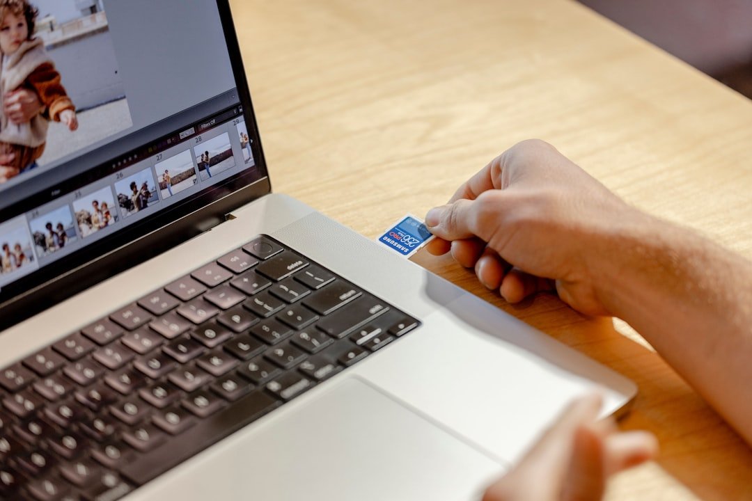 A person using a laptop computer on a wooden table