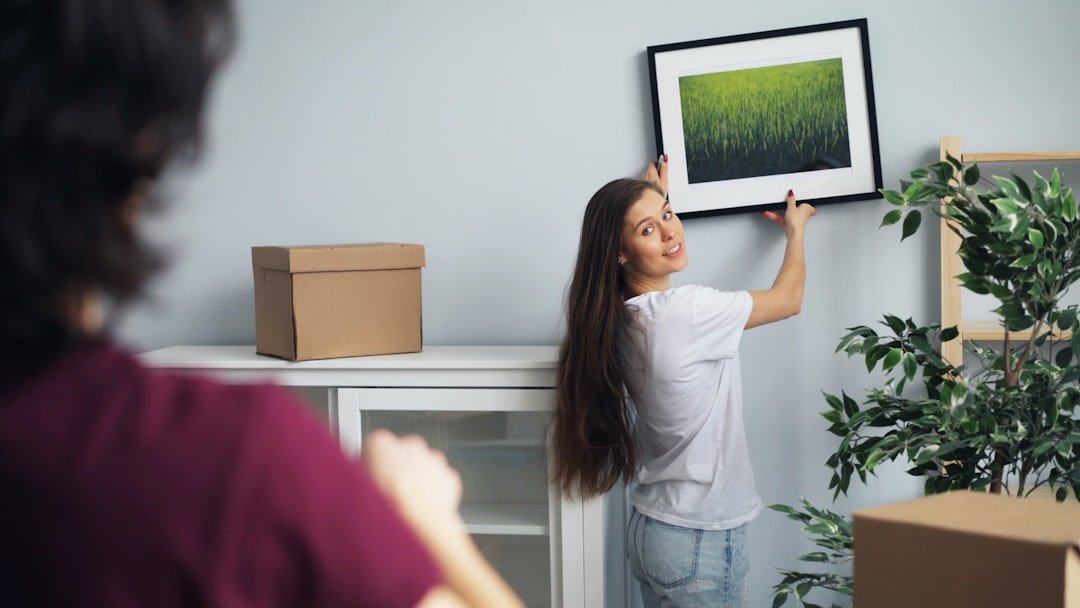 a woman hanging a picture on a wall