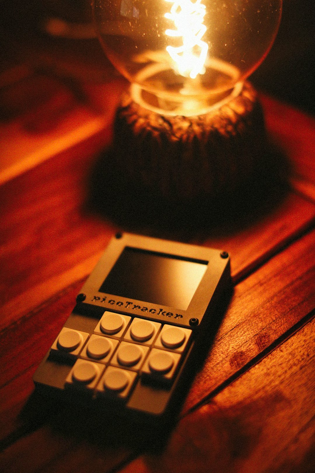 An electronic device sits beneath a glowing lamp.