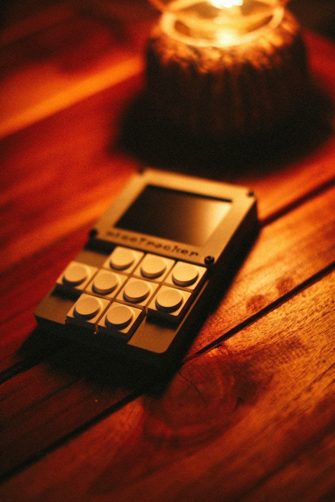 A device with buttons sits near candlelight.