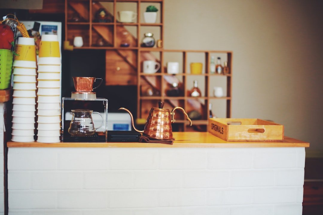 a counter top with a coffee pot and some cups on it