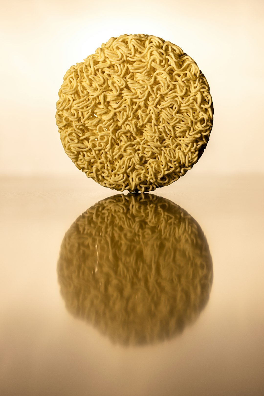 a round object made out of noodles on a reflective surface