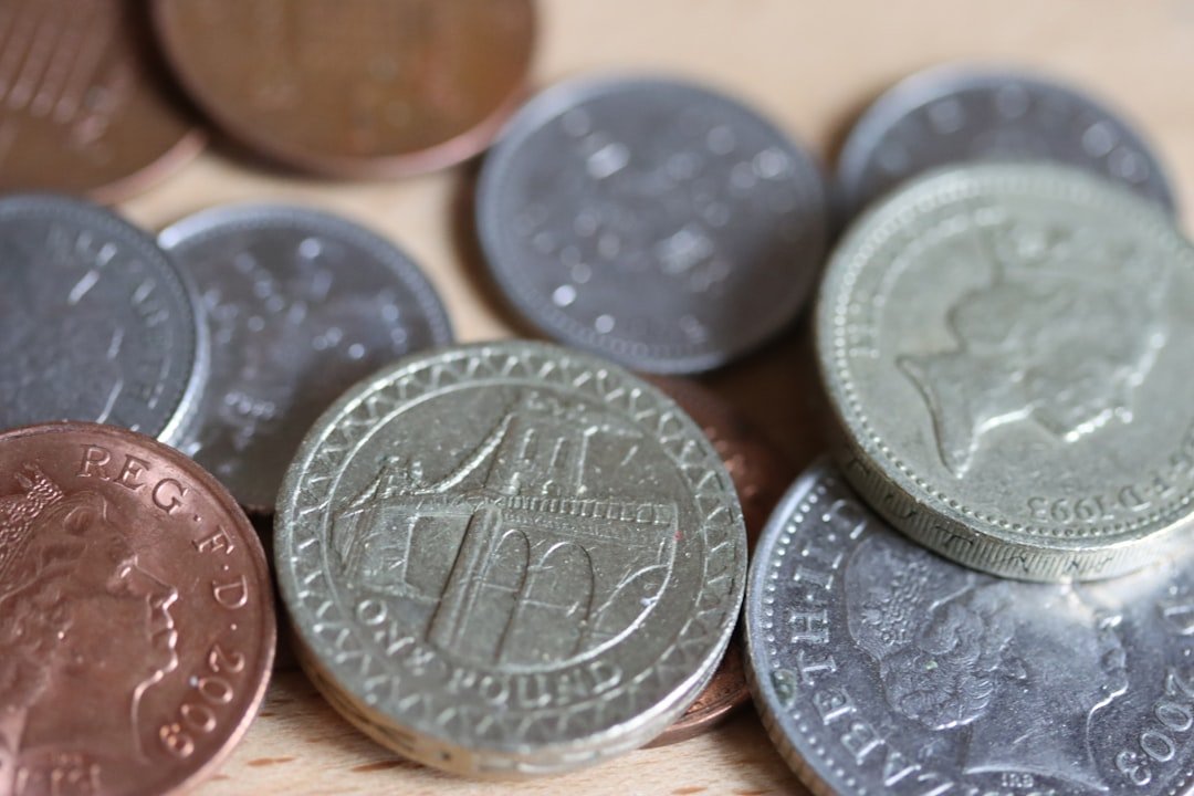 a pile of british coins sitting on top of a wooden table